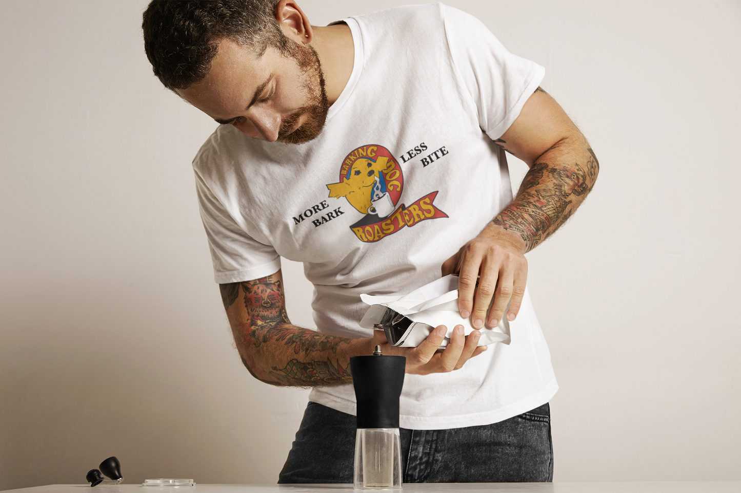 Classic Logo Tee - Barking Dog Roasters Man Pouring coffee into hand grinder wearing white Logo tee
